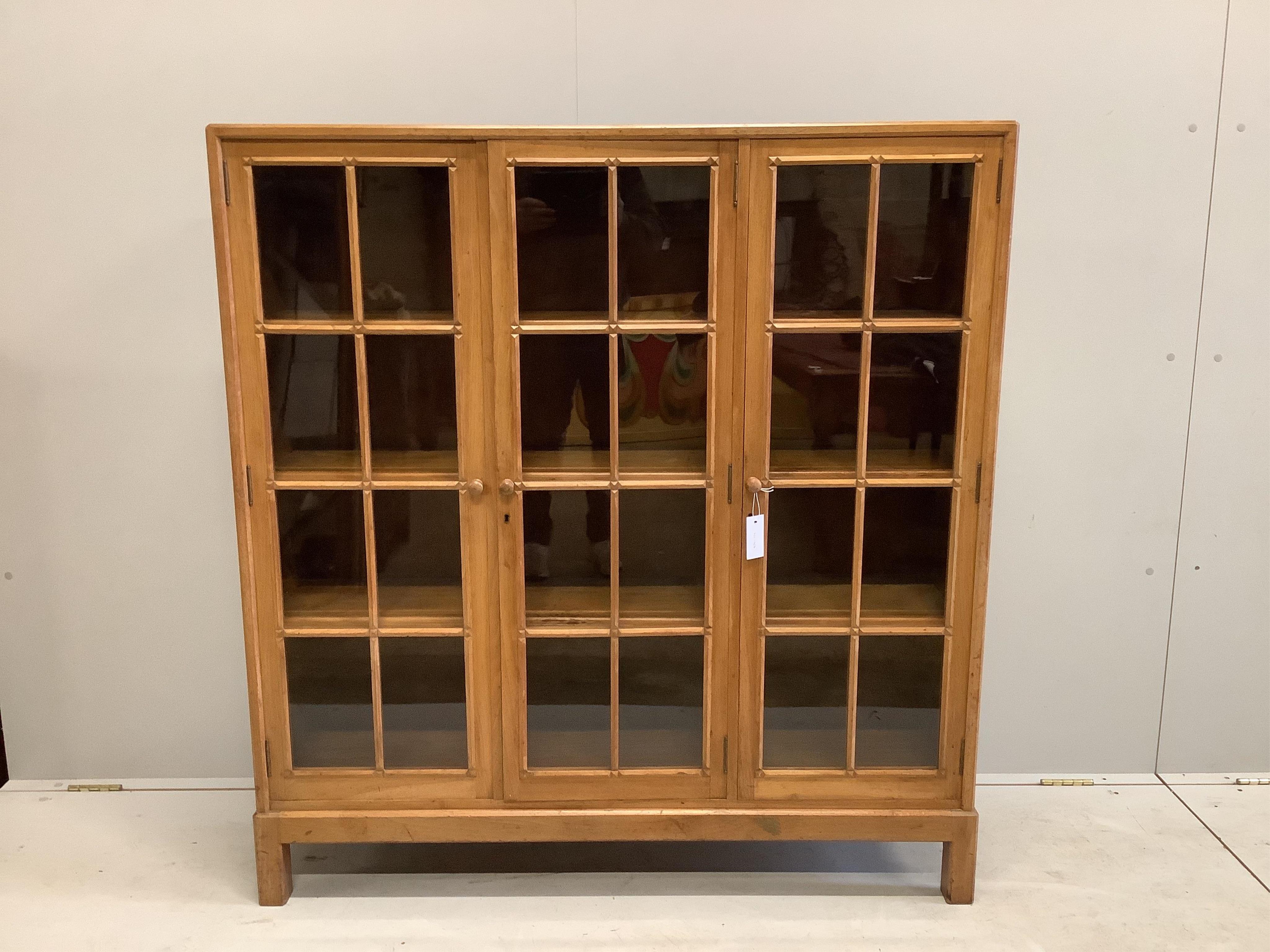 An early 20th century Heal & Son, London glazed walnut three door bookcase, width 122cm, depth 29cm, height 130cm. Condition - fair to good